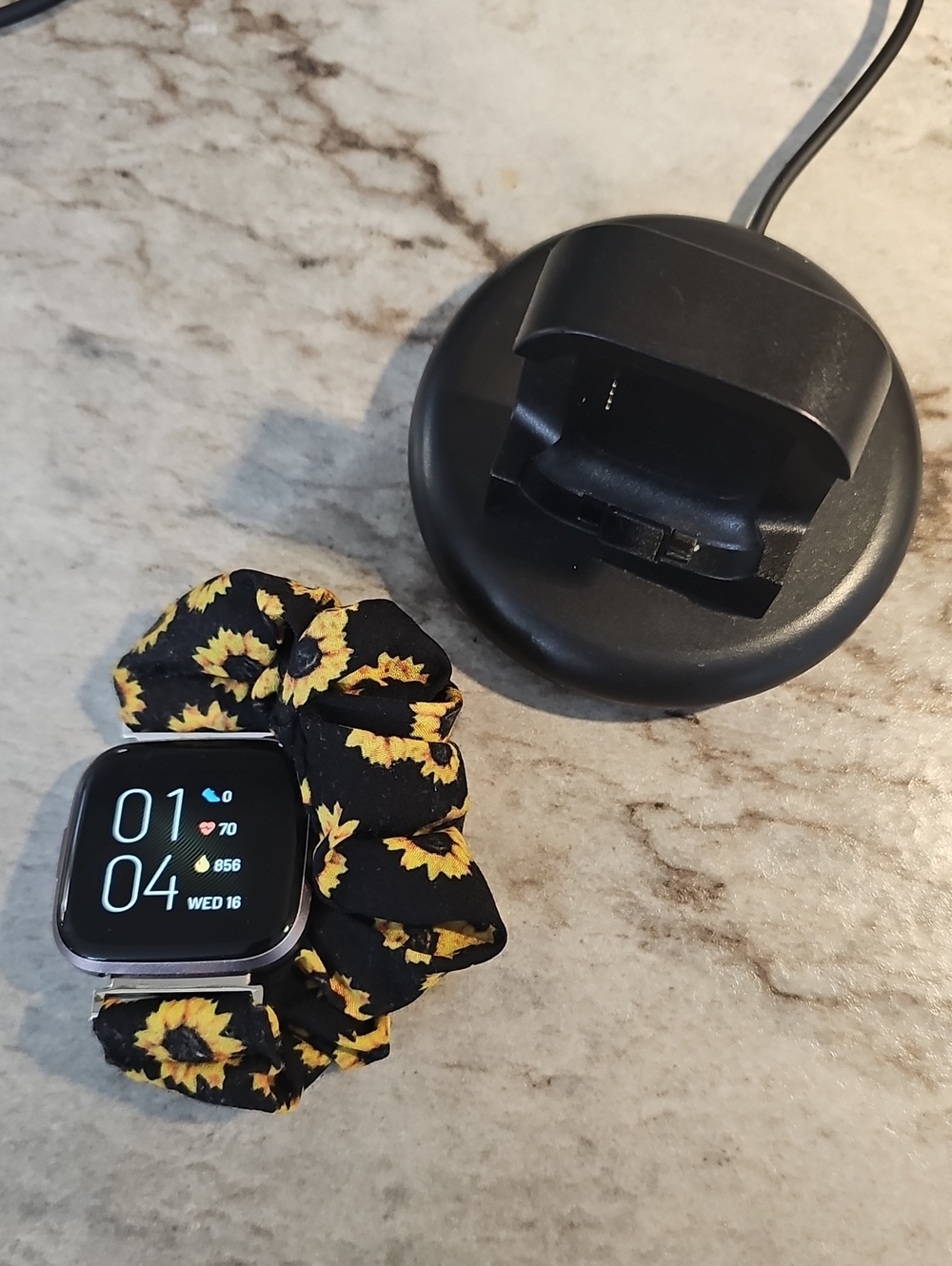 Fitbit Versa 2 smartwatch with black and yellow sunflower scrunchie band